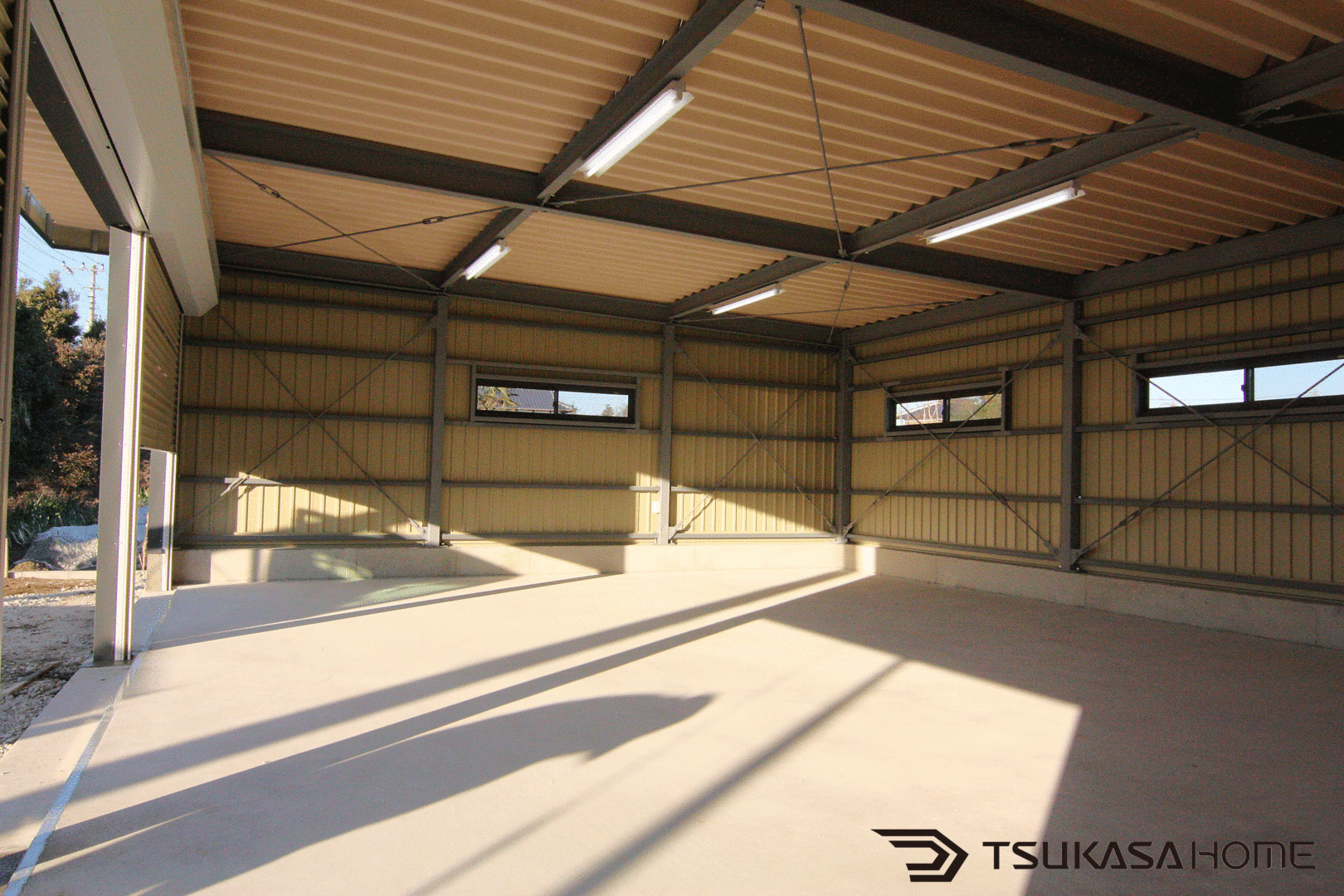茨城県常総市の鉄骨ガレージ内部。3台駐車対応の土間仕上げと採光窓がある広い空間
