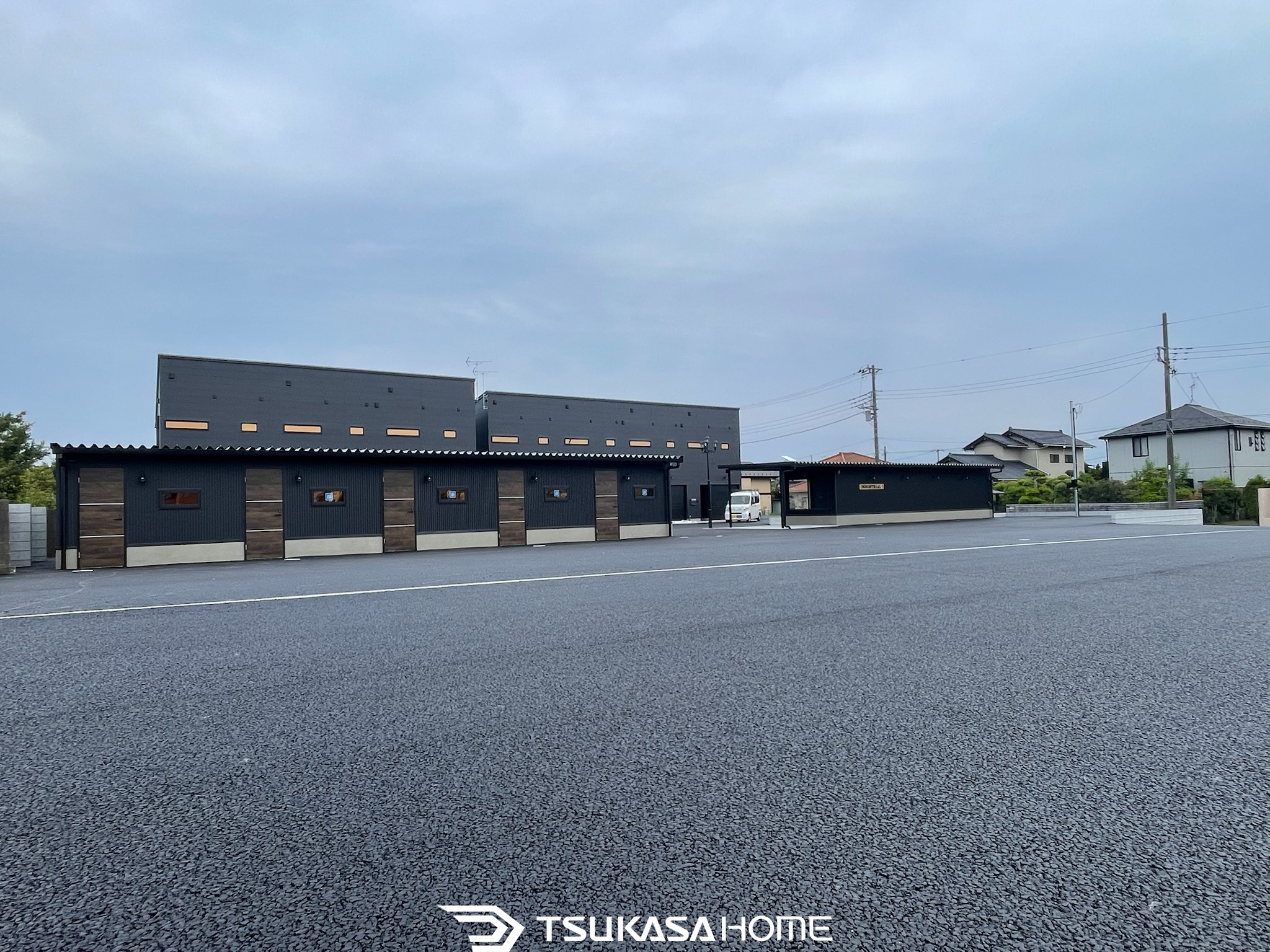 黒い外壁と木目のアクセントを組み合わせた完成済みバイクガレージ外観。ツカサホーム施工。