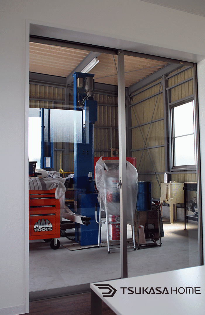 千葉県四街道市の鉄骨ガレージ施工例。ホビールームからガラス越しにガレージ内の車や工具を見渡せるレイアウト
