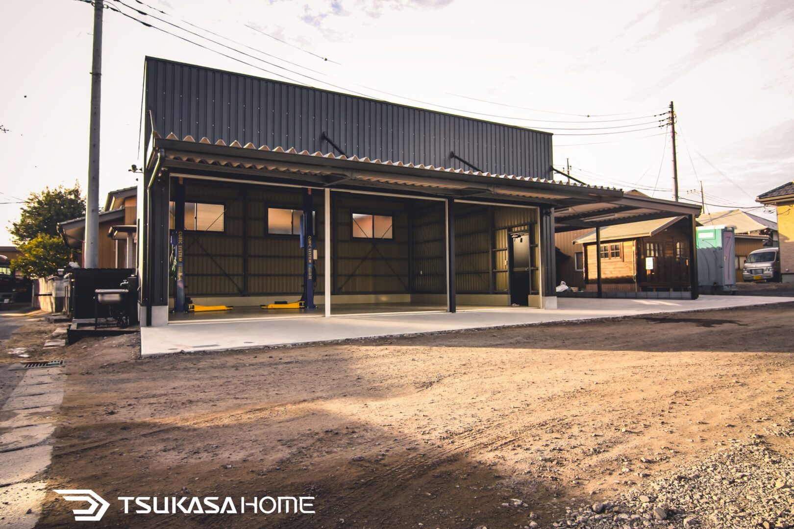 鉄骨造で建てたシャッター付きガレージとカーポートの外観。愛車を雨風から守る倉庫ガレージ
