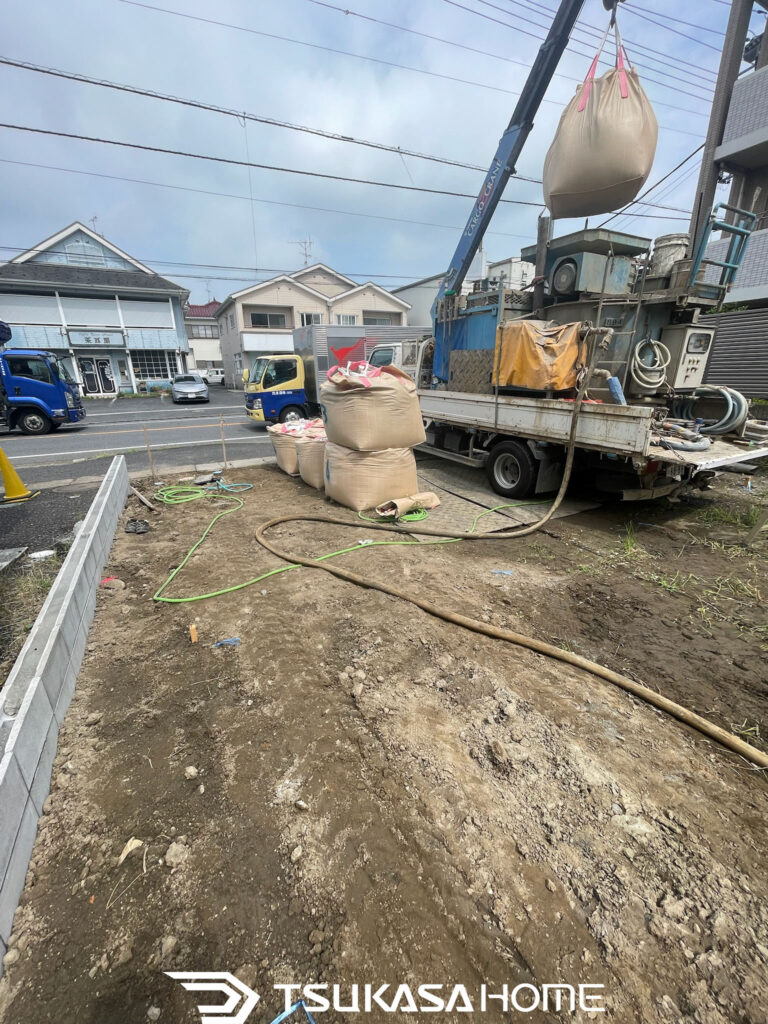 流山市のガレージ建築現場で改良材を搬入し柱状改良工事を行っている作業風景
